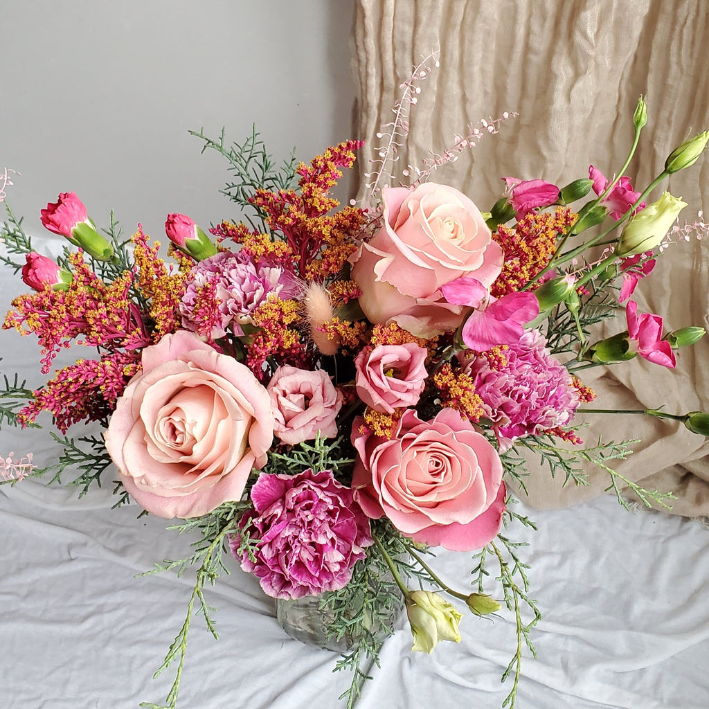 flower arrangement in a vase with pink and blush flowers: roses, carnations, lisianthus. 